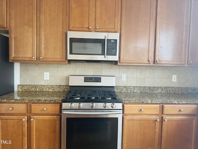 1150 Brookhill Way, Cary, NC 27519 - kitchen with stainless steel appliances, tasteful backsplash, dark stone counters, and brown cabinetry