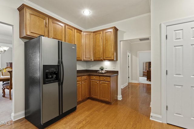 400 Indian Elm Ln, Cary, NC 27519 - kitchen featuring stainless steel refrigerator with ice dispenser, brown cabinetry, light wood-style floors, dark countertops, and crown molding
