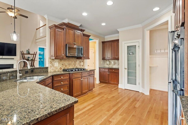 10012 San Remo Pl, Wake Forest, NC 27587 - kitchen with stainless steel appliances, a ceiling fan, dark stone counters, light wood-style flooring, and brown cabinetry