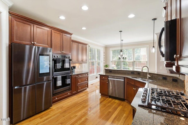 10012 San Remo Pl, Wake Forest, NC 27587 - kitchen featuring appliances with stainless steel finishes, light wood-type flooring, ornamental molding, recessed lighting, and dark stone counters