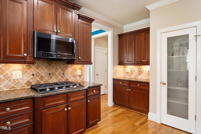 10012 San Remo Pl, Wake Forest, NC 27587 - kitchen with appliances with stainless steel finishes, light wood-type flooring, dark stone countertops, decorative backsplash, and crown molding