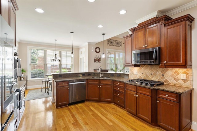 10012 San Remo Pl, Wake Forest, NC 27587 - kitchen featuring appliances with stainless steel finishes, light wood-style flooring, a peninsula, ornamental molding, and decorative light fixtures
