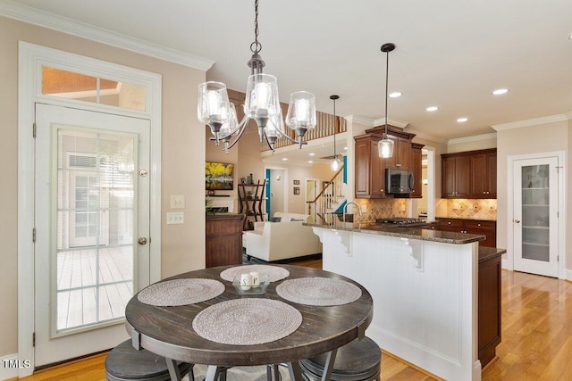 10012 San Remo Pl, Wake Forest, NC 27587 - kitchen with stainless steel appliances, a breakfast bar area, tasteful backsplash, a peninsula, and a chandelier