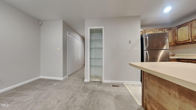933 Creek Side, Fayetteville, NC 28303 - kitchen featuring light carpet, light countertops, freestanding refrigerator, and brown cabinetry