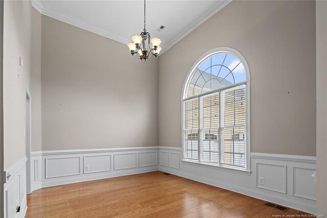 259 Rolling Pines Dr, Spring Lake, NC 28390 - spare room with a chandelier, plenty of natural light, ornamental molding, a wainscoted wall, and light wood finished floors