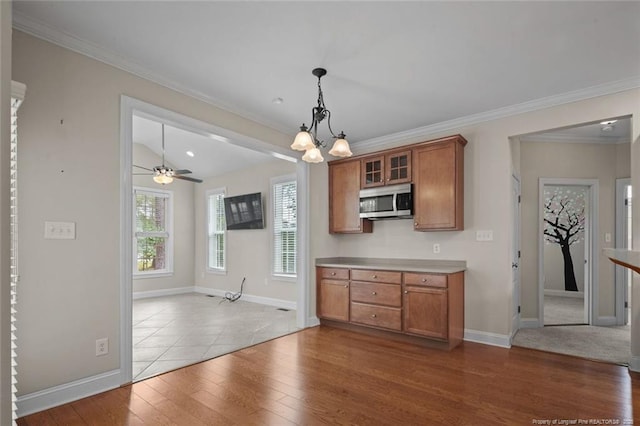 259 Rolling Pines Dr, Spring Lake, NC 28390 - kitchen with stainless steel microwave, brown cabinets, dark wood-type flooring, glass insert cabinets, and hanging light fixtures