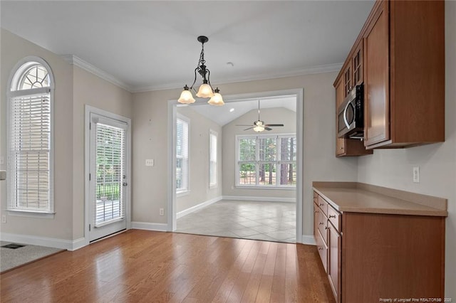 259 Rolling Pines Dr, Spring Lake, NC 28390 - kitchen featuring stainless steel microwave, brown cabinets, light wood-style floors, pendant lighting, and ornamental molding