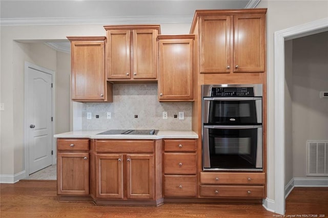 259 Rolling Pines Dr, Spring Lake, NC 28390 - kitchen with black electric stovetop, stainless steel double oven, wood finished floors, crown molding, and backsplash