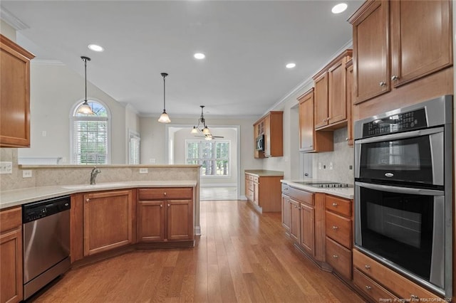 259 Rolling Pines Dr, Spring Lake, NC 28390 - kitchen featuring stainless steel appliances, crown molding, a peninsula, brown cabinetry, and backsplash