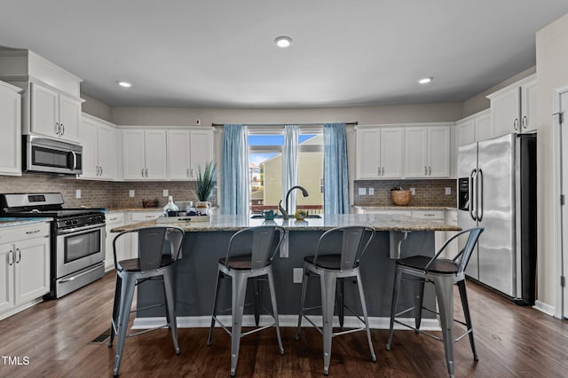 417 Austin View Blvd, Wake Forest, NC 27587 - kitchen with stainless steel appliances, a center island with sink, white cabinetry, backsplash, and dark wood-style floors