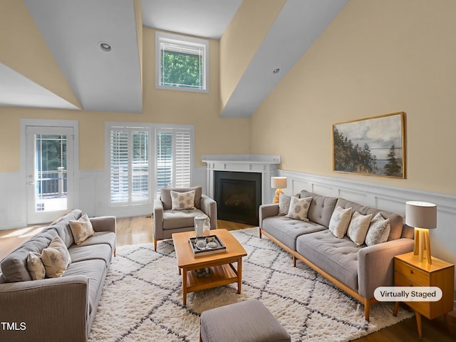 495 Ruth Cir, Fuquay Varina, NC 27526 - living area featuring a wainscoted wall, wood finished floors, a fireplace, high vaulted ceiling, and a decorative wall