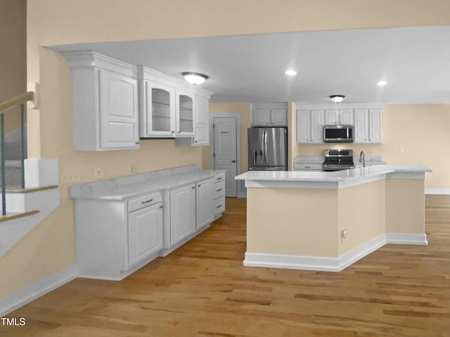 495 Ruth Cir, Fuquay Varina, NC 27526 - kitchen with stainless steel appliances, light wood finished floors, white cabinets, glass insert cabinets, and recessed lighting
