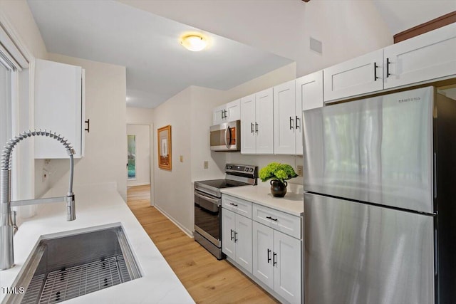 1403 Meadow Ln, Chapel Hill, NC 27516 - kitchen featuring appliances with stainless steel finishes, light wood-type flooring, white cabinets, and light countertops