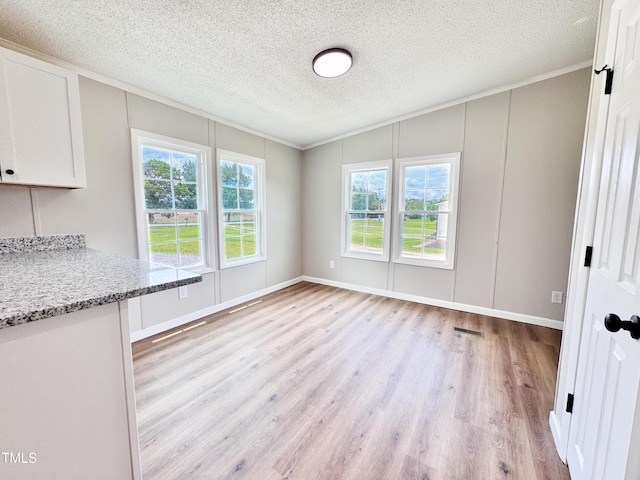6283 US-258, Tarboro, NC 27886 - unfurnished dining area featuring light wood-style floors, a decorative wall, a textured ceiling, ornamental molding, and vaulted ceiling