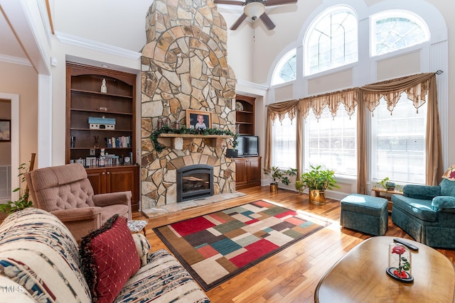 5920 Two Pines Trl, Wake Forest, NC 27587 - living area featuring ornamental molding, hardwood / wood-style flooring, a stone fireplace, a ceiling fan, and a high ceiling