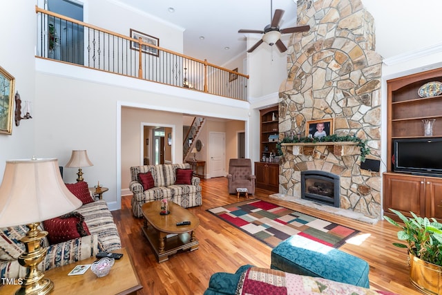 5920 Two Pines Trl, Wake Forest, NC 27587 - living area with ceiling fan, wood finished floors, crown molding, a stone fireplace, and a high ceiling