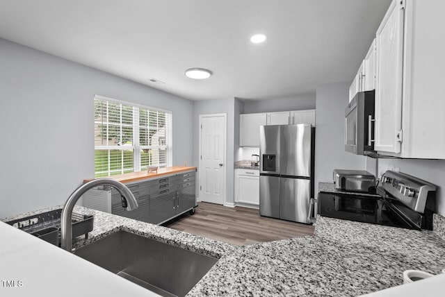 611 Quartz Dr, Durham, NC 27703 - kitchen featuring appliances with stainless steel finishes, wood finished floors, white cabinets, light stone counters, and recessed lighting