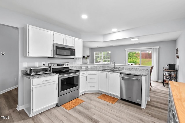 611 Quartz Dr, Durham, NC 27703 - kitchen with stainless steel appliances, a peninsula, white cabinetry, recessed lighting, and light wood-type flooring