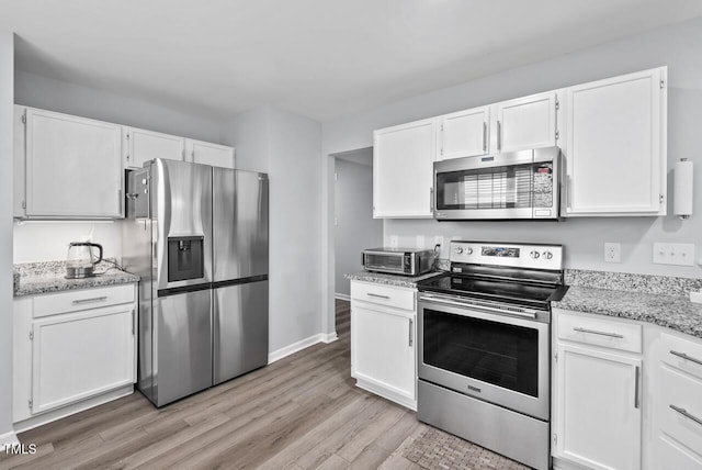 611 Quartz Dr, Durham, NC 27703 - kitchen with appliances with stainless steel finishes, light wood-type flooring, white cabinetry, and light stone countertops