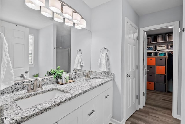 611 Quartz Dr, Durham, NC 27703 - full bathroom with double vanity, wood finished floors, a walk in closet, and a shower