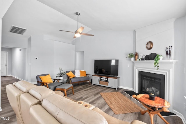611 Quartz Dr, Durham, NC 27703 - living room featuring wood finished floors, vaulted ceiling, a ceiling fan, and a glass covered fireplace