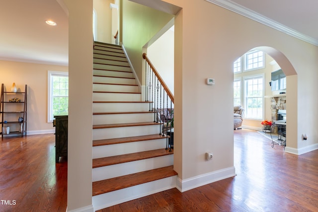 9701 Corktree Ct, Wake Forest, NC 27587 - stairway with a stone fireplace, crown molding, wood finished floors, arched walkways, and recessed lighting
