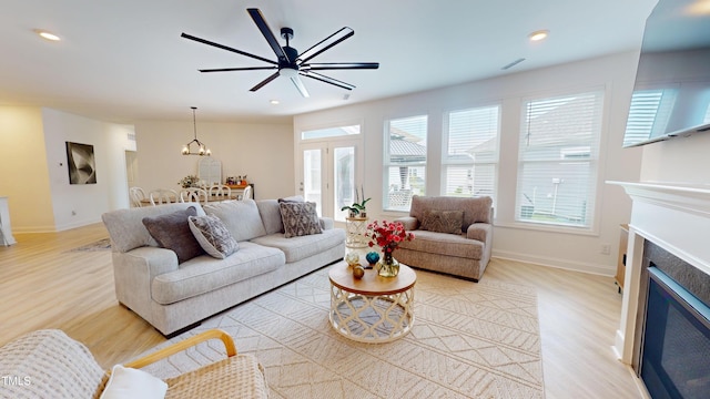 1720 Pinecliff Ct, Fuquay Varina, NC 27526 - living room featuring light wood-style flooring, a glass covered fireplace, ceiling fan, recessed lighting, and a chandelier