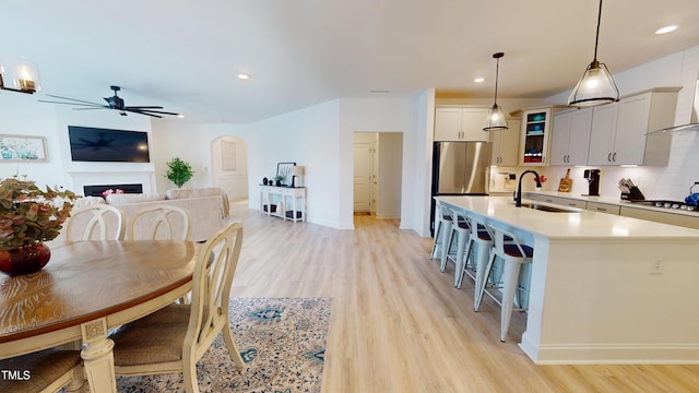 1720 Pinecliff Ct, Fuquay Varina, NC 27526 - dining area featuring light wood-type flooring, a ceiling fan, recessed lighting, a fireplace, and arched walkways