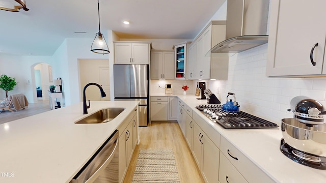 1720 Pinecliff Ct, Fuquay Varina, NC 27526 - kitchen featuring wall chimney range hood, stainless steel appliances, arched walkways, light countertops, and light wood-style floors