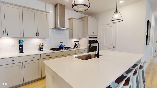 1720 Pinecliff Ct, Fuquay Varina, NC 27526 - kitchen with wall chimney exhaust hood, stainless steel gas stovetop, light wood finished floors, tasteful backsplash, and a kitchen breakfast bar