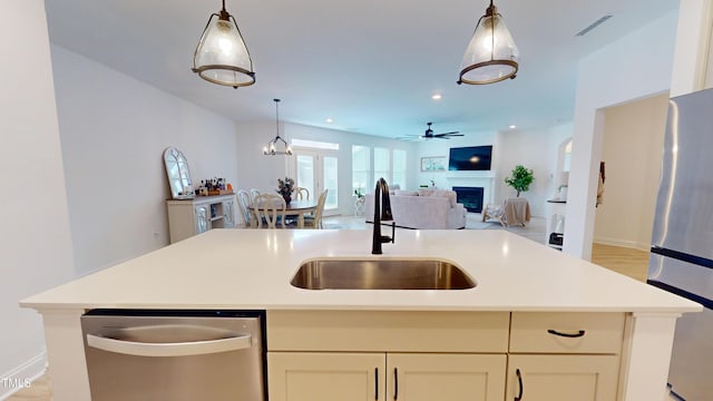 1720 Pinecliff Ct, Fuquay Varina, NC 27526 - kitchen with appliances with stainless steel finishes, open floor plan, a fireplace, a ceiling fan, and hanging light fixtures