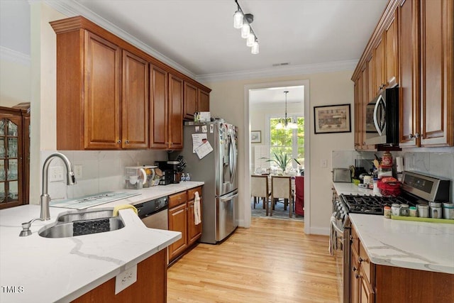 23 Northern Way Ct, Durham, NC 27712 - kitchen featuring stainless steel appliances, light wood finished floors, brown cabinetry, decorative backsplash, and ornamental molding