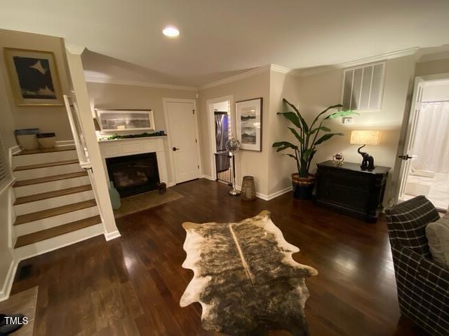 627 New Rd, Raleigh, NC 27608 - living room with crown molding, wood finished floors, a fireplace with flush hearth, stairs, and recessed lighting