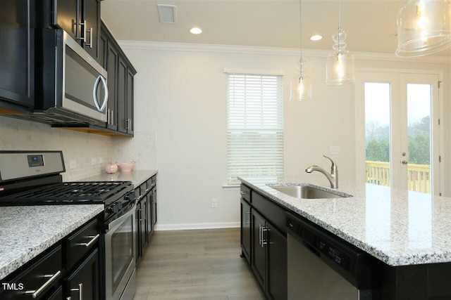 319 Great Northern Sta, Apex, NC 27502 - kitchen featuring appliances with stainless steel finishes, wood finished floors, french doors, decorative backsplash, and an island with sink