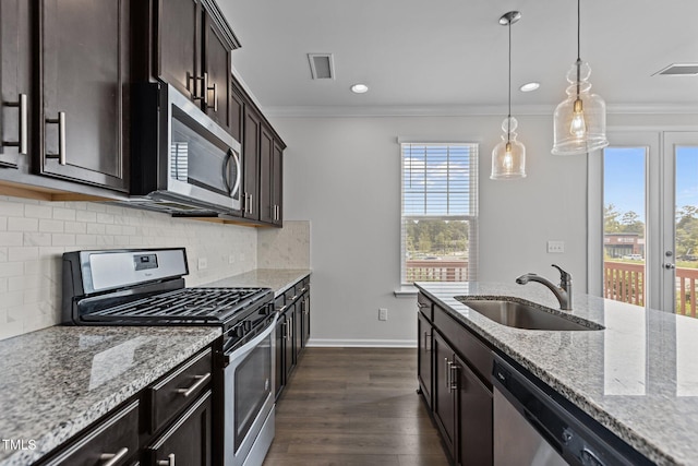 319 Great Northern Sta, Apex, NC 27502 - kitchen featuring appliances with stainless steel finishes, crown molding, dark wood-style floors, light stone countertops, and decorative light fixtures