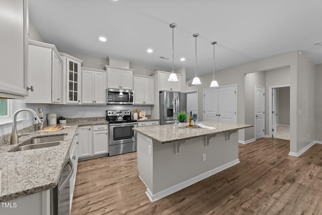 119 Yadkin St, Clayton, NC 27520 - kitchen featuring stainless steel appliances, a kitchen island, white cabinetry, a kitchen breakfast bar, and light wood-type flooring
