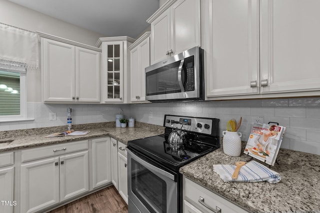 119 Yadkin St, Clayton, NC 27520 - kitchen featuring appliances with stainless steel finishes, white cabinets, glass insert cabinets, and tasteful backsplash