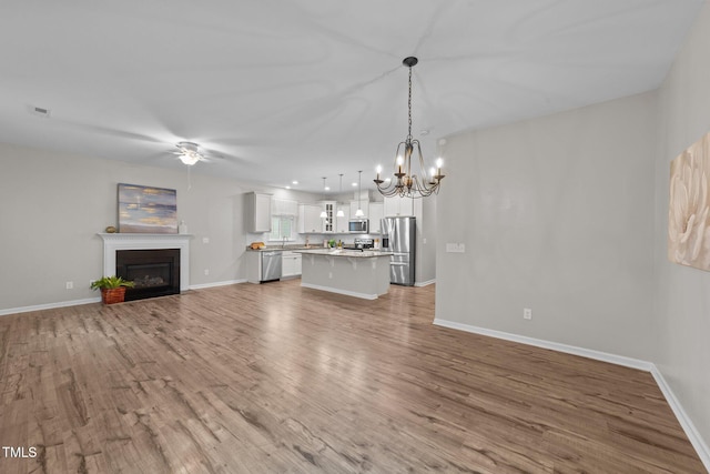 119 Yadkin St, Clayton, NC 27520 - unfurnished living room with a chandelier, ceiling fan, wood finished floors, and a fireplace