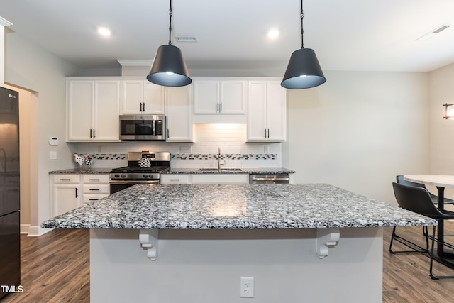 9 Moss Side Ter, Durham, NC 27703 - kitchen with appliances with stainless steel finishes, a kitchen breakfast bar, tasteful backsplash, dark wood finished floors, and recessed lighting