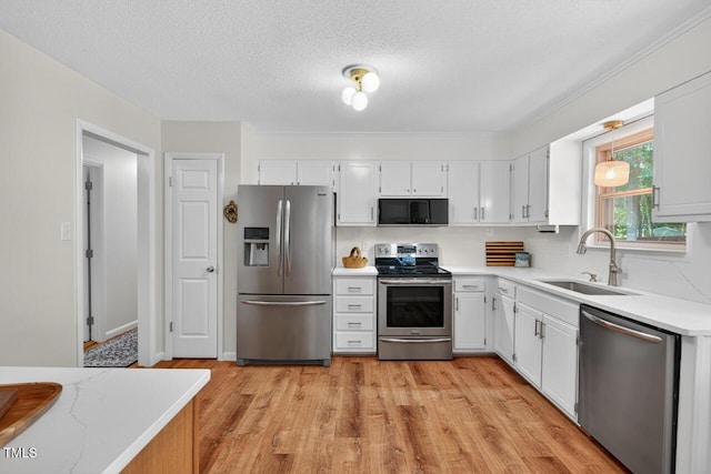 810 Royal Oaks Dr, Durham, NC 27712 - kitchen featuring appliances with stainless steel finishes, white cabinets, light wood-style flooring, tasteful backsplash, and a textured ceiling