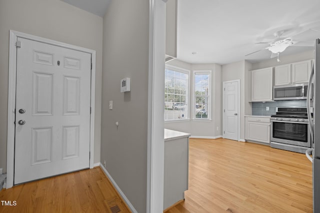 400 Nottinghill Walk, Apex, NC 27502 - kitchen featuring appliances with stainless steel finishes, white cabinets, light countertops, light wood-style flooring, and decorative backsplash