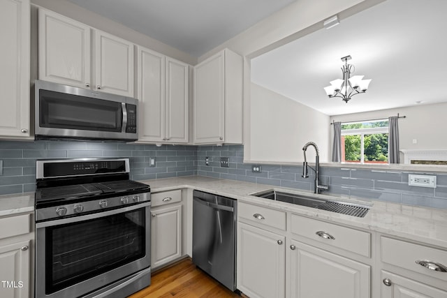 400 Nottinghill Walk, Apex, NC 27502 - kitchen with appliances with stainless steel finishes, a chandelier, white cabinets, backsplash, and light stone countertops