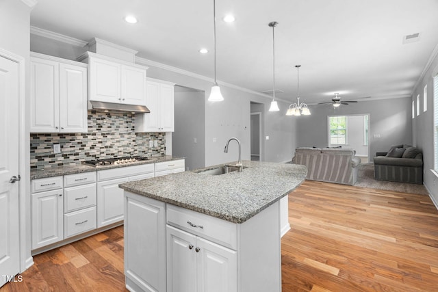 1019 Santiago St, Durham, NC 27703 - kitchen with light wood finished floors, stainless steel gas stovetop, a ceiling fan, backsplash, and an island with sink