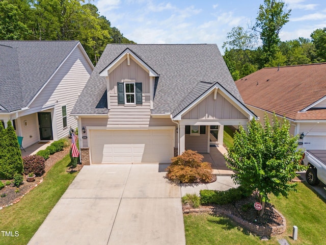 1019 Santiago St, Durham, NC 27703 - view of front of home with board and batten siding, concrete driveway, roof with shingles, covered porch, and a front lawn