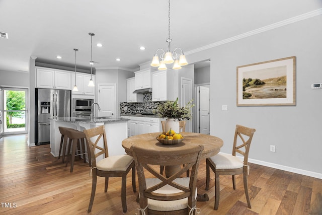 1019 Santiago St, Durham, NC 27703 - dining room featuring ornamental molding, light wood-type flooring, recessed lighting, and a chandelier
