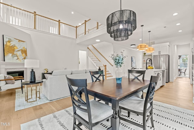 525 Kings Lake Way, Durham, NC 27703 - dining area with stairway, light wood finished floors, recessed lighting, a glass covered fireplace, and a high ceiling