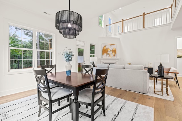 525 Kings Lake Way, Durham, NC 27703 - dining space with light wood-type flooring, a towering ceiling, a fireplace, and a chandelier