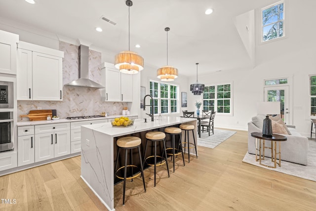 525 Kings Lake Way, Durham, NC 27703 - kitchen with wall chimney range hood, light wood finished floors, white cabinets, recessed lighting, and a breakfast bar