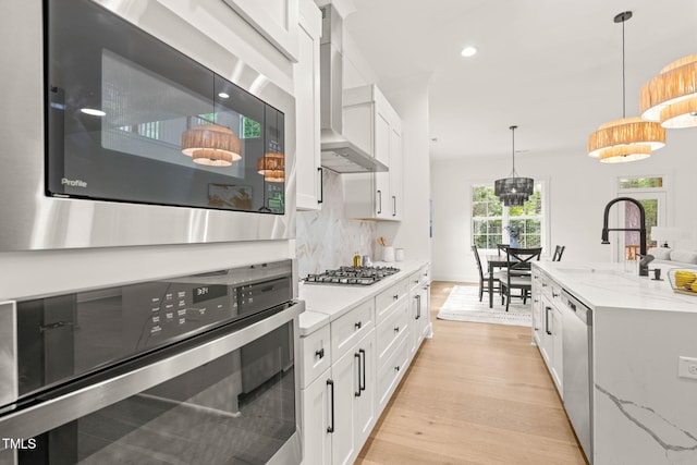 525 Kings Lake Way, Durham, NC 27703 - kitchen featuring stainless steel appliances, wall chimney range hood, light wood-style floors, decorative backsplash, and light stone countertops