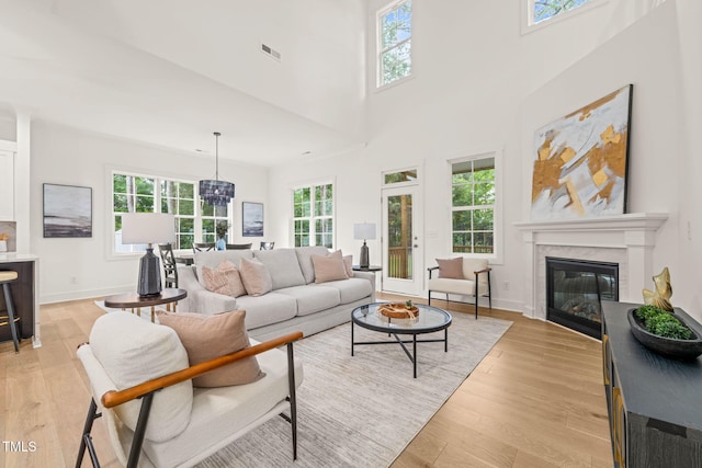 525 Kings Lake Way, Durham, NC 27703 - living area featuring light wood-style floors, a glass covered fireplace, a high ceiling, and a chandelier